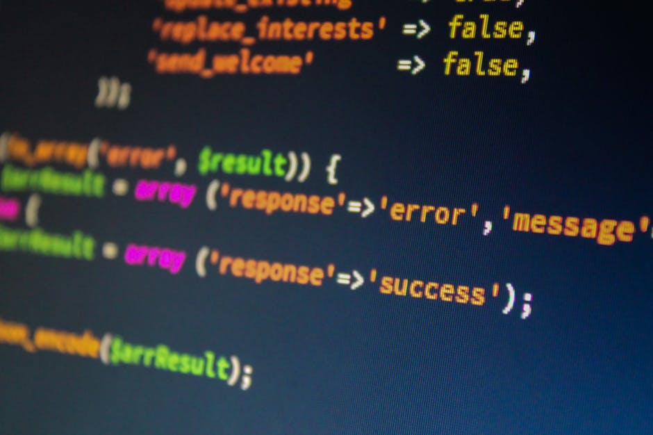Close-up view of a computer screen displaying colorful programming code with syntax highlighting. The code includes lines with keywords in orange, variables in green, and strings in pink, set against